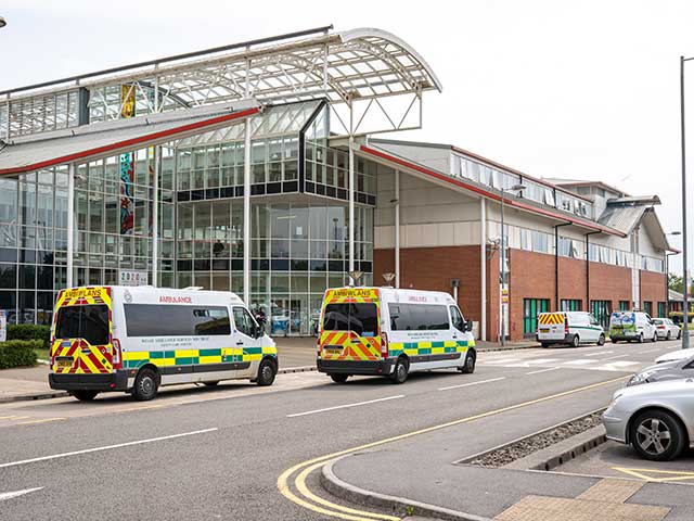 A hospital entrance surrounded by vehicles.