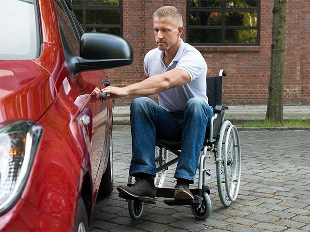 A wheelchair user getting into a car.