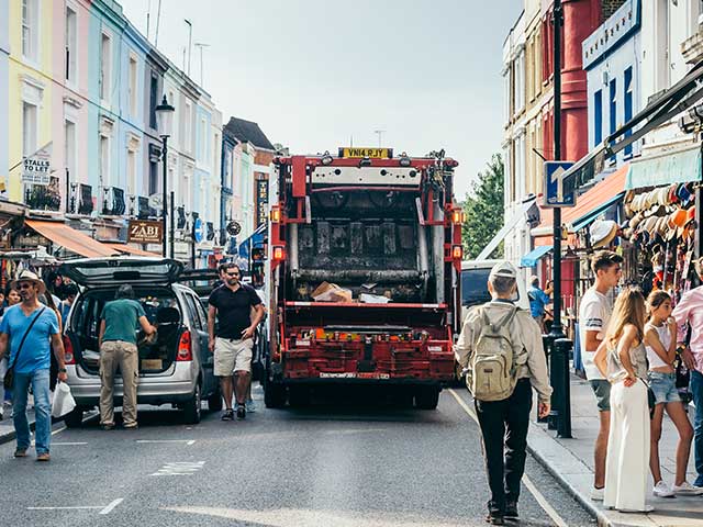 A refuse lorry travelling down a bustling street.